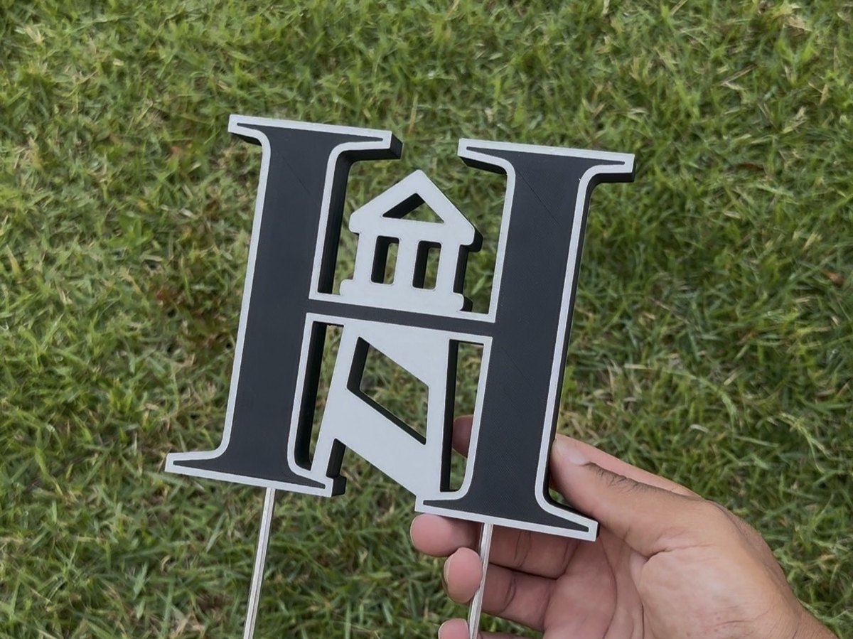 Initial-and-lighthouse marker staked in tee-box grass