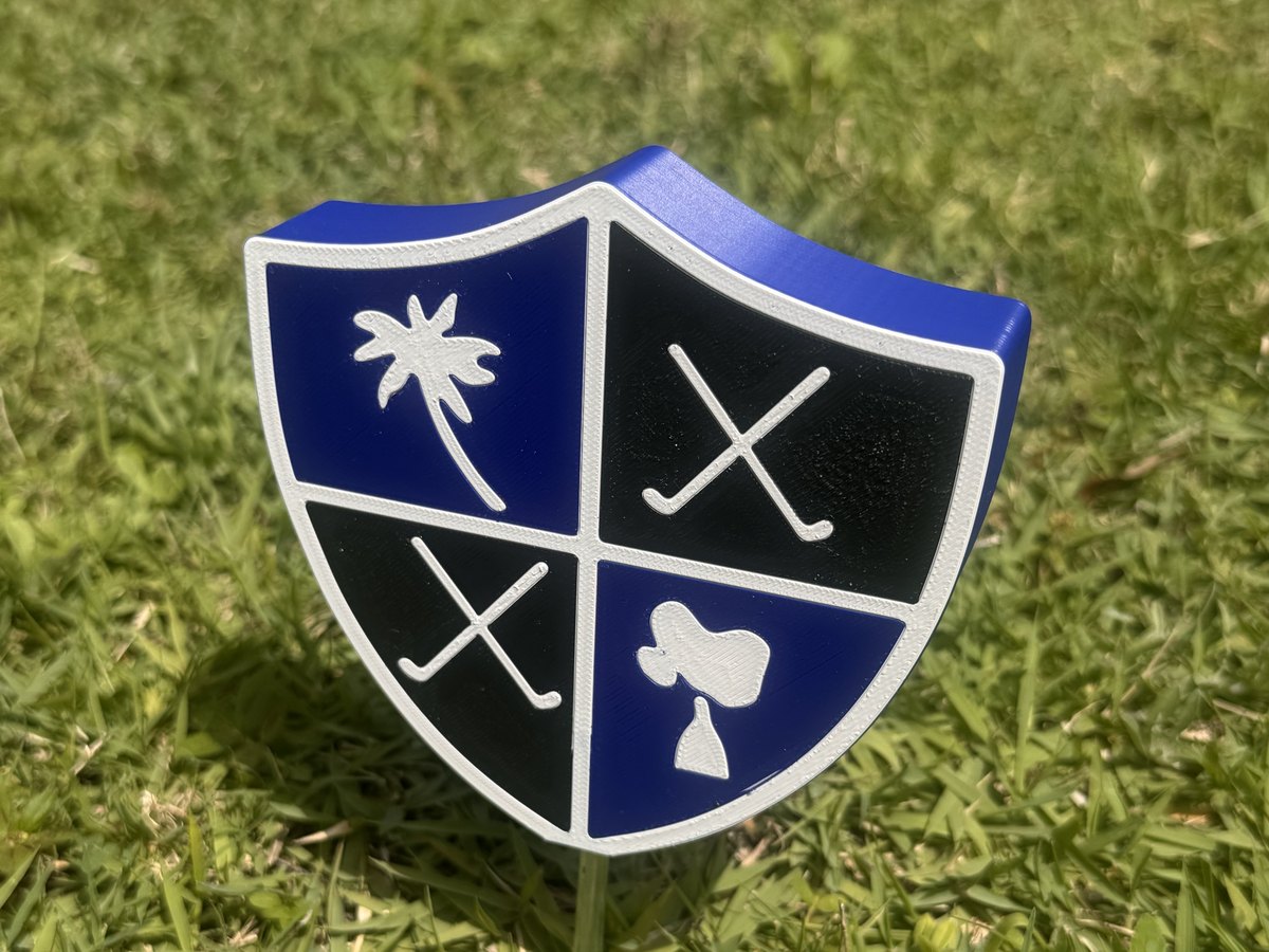 Quartered club-crest shield marker staked on a tee box